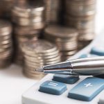 silver ball pen on calculator with stack coins background